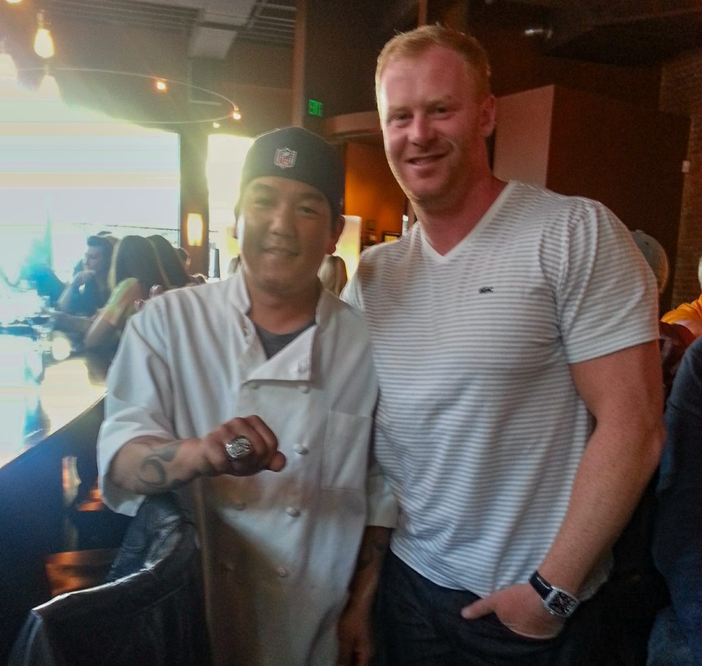 Mike Hempel (left) puts on the Super Bowl ring of Seattle Seahawks punter Jon Ryan before he began to let his hair grow and grow. (Photo Courtesy: Mike Hempel)