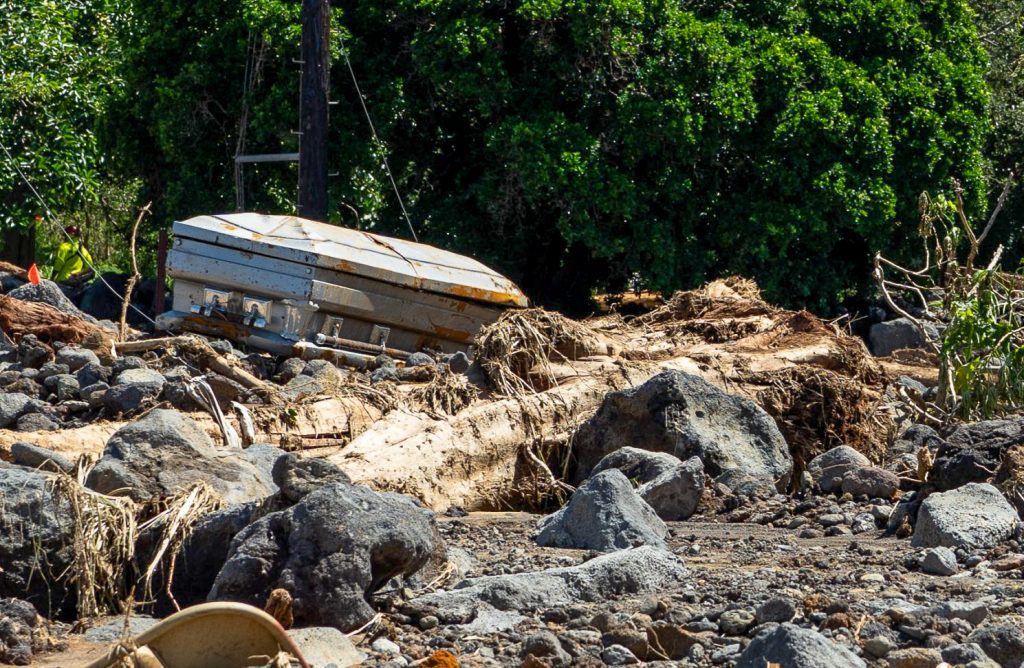 A coffin sits atop rubble above the Punalu‘u Bake Shop after Hurricane Lala flooded Nā‘ālehu on Aug. 15, 2026, washing out the Nā‘ālehu Cemetery. (Tiffany DeMasters/Big Island Now)