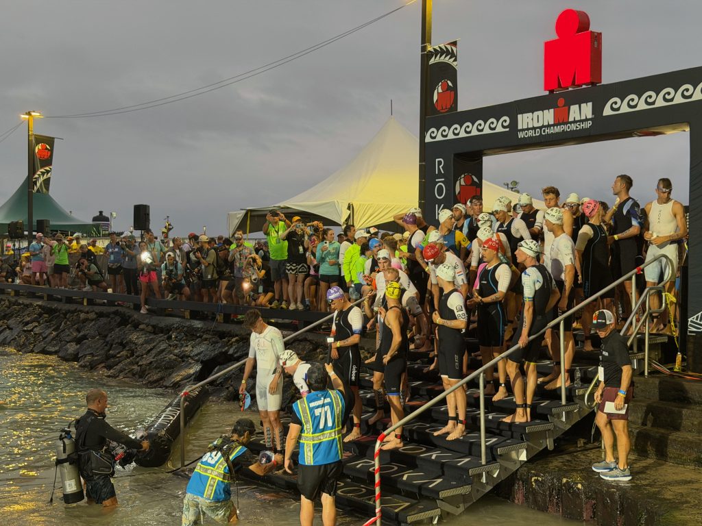 The professional men triathletes enter the water before the start of the 2.4-mile swim in Kailua Bay, the first leg of the Ironman World Championship in Kailua-Kona on Oct. 10, 2026. (Tiffany DeMasters/Big Island Now)
